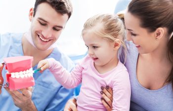 Dentist teaching girl how to brush teeth