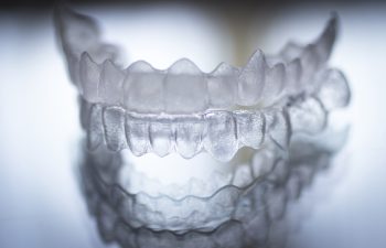 Invisible dental teeth brackets tooth aligners plastic braces retainers to straighten teeth. Orthodontic temporary removable straighteners in dental office dentists surgery clinic.Artistic color photo in creative blue tones. ** Note: Soft Focus at 100%,