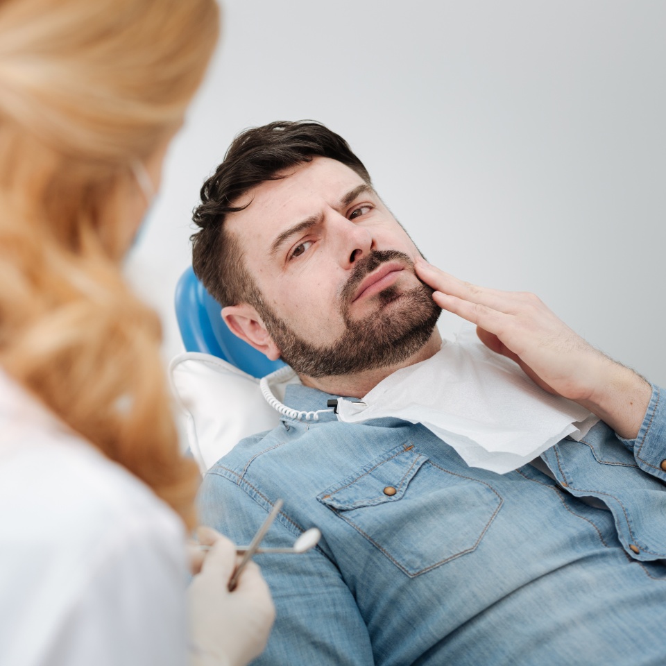 I cannot take it any longer. Disturbed handsome upset man telling a doctor about his concerns while paying her a regular visit and sitting in dentists chair