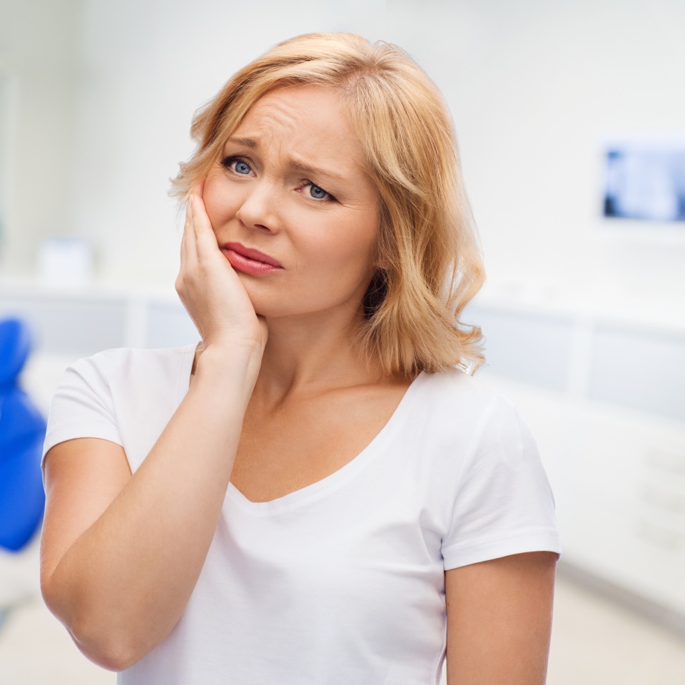people, healthcare, dentistry and problem concept - unhappy woman suffering toothache over dental office background