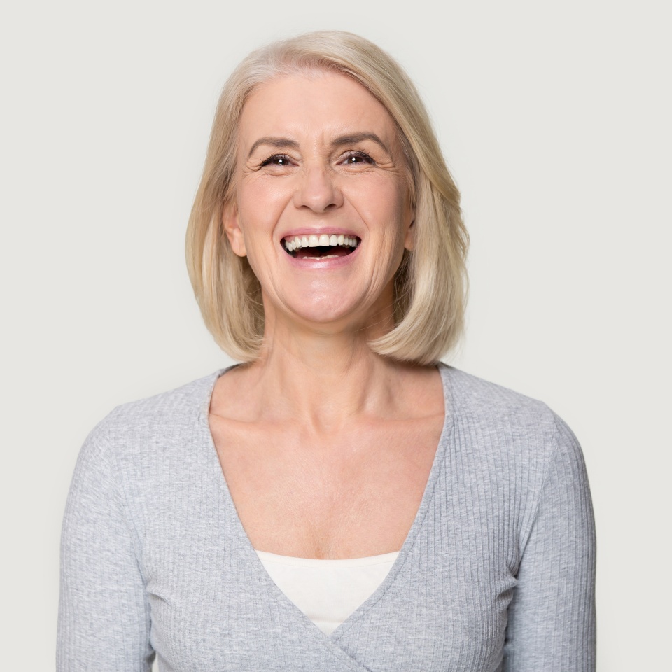 Head shot portrait overjoyed blond middle aged female smiling look at camera laughing feels happy pose isolated on grey studio background, advertise clinic procedure dental care prosthesis for seniors