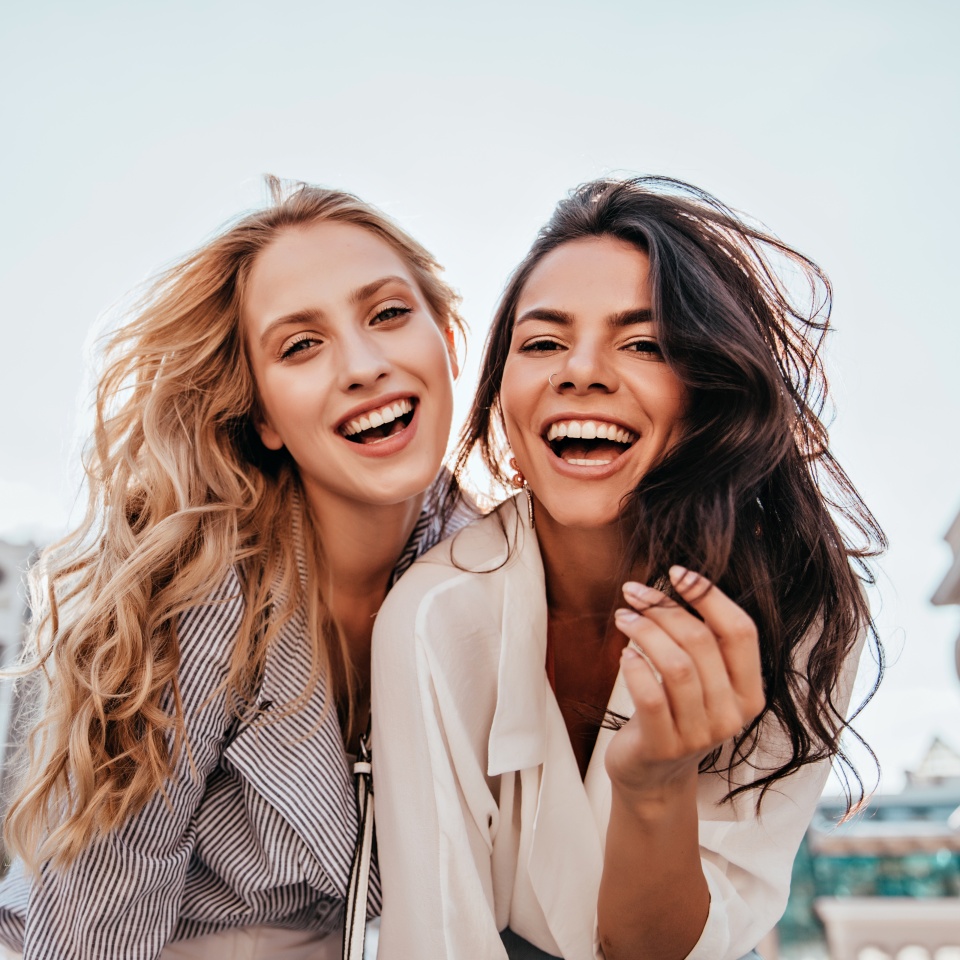 Appealing long-haired girls posing on sky background. Laughing ladies enjoying weekend together.