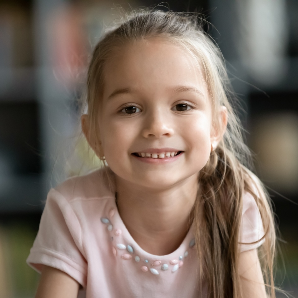 Head shot portrait smiling pretty little girl looking at camera, happy preschool child playing with camera, recording vlog, making video call, chatting online with relatives, using webcam