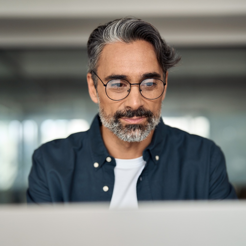 Busy mature business man, middle aged professional executive, older entrepreneur investor wearing glasses looking at laptop computer thinking on financial market working online in office. Close up.