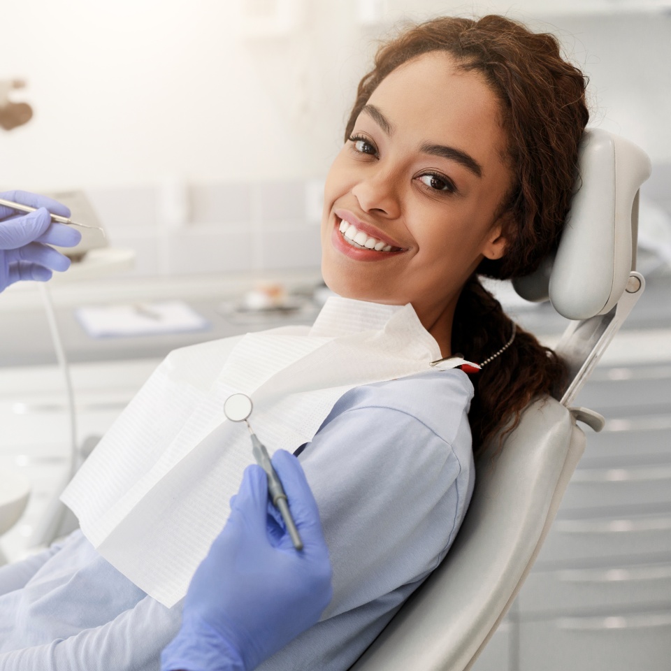 Pretty black happy woman in dentist chair ready for regular check up in modern stomatological clinic